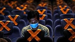 رجل يراقب هاتفه داخل قاعة سينما في العاصمة الاندونيسية جاكارتا حيث وضعت على المقاعد علامات التباعد الاجتماعي. 2020/10/23
