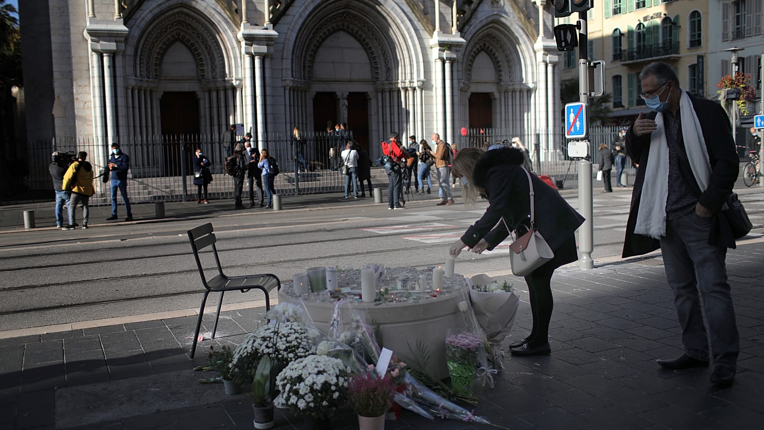 A woman lights a candles in front of the Notre Dame church, in Nice, France, Friday, Oct. 30, 2020. 