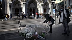 A woman lights a candles in front of the Notre Dame church, in Nice, France, Friday, Oct. 30, 2020. 