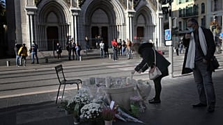 A woman lights a candles in front of the Notre Dame church, in Nice, France, Friday, Oct. 30, 2020.