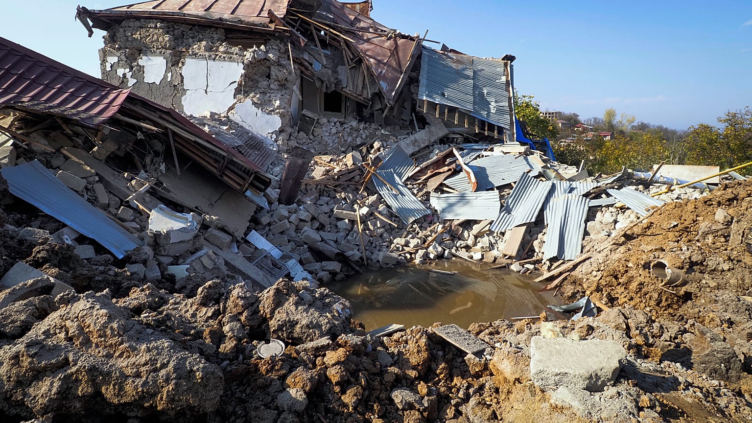 A bomb crater near a house destroyed by shelling by Azerbaijan's forces during a military conflict in Shushi, outside Stepanakert, the separatist region of Nagorno-Karabakh
