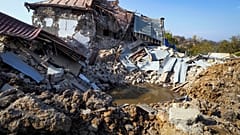 A bomb crater near a house destroyed by shelling by Azerbaijan's forces during a military conflict in Shushi, outside Stepanakert, the separatist region of Nagorno-Karabakh