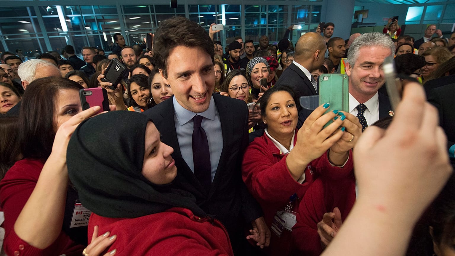 Canadian Prime Minister Justin Trudeau, centre, poses for a selfies with workers before he greets refugees from Syria at Pearson International airport, in Toronto