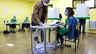 A man wearing a face mask to help curb the spread of the coronavirus, casts his ballot at a polling station during the parliamentary elections in Tbilisi, Georgia, Saturday, O