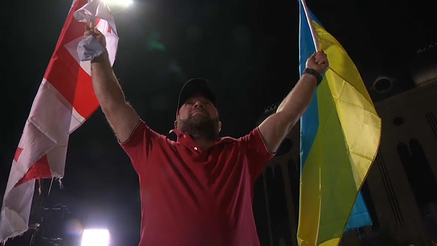 Un partidario de la oposición sostiene una bandera de Georgia y otra de Ucrania