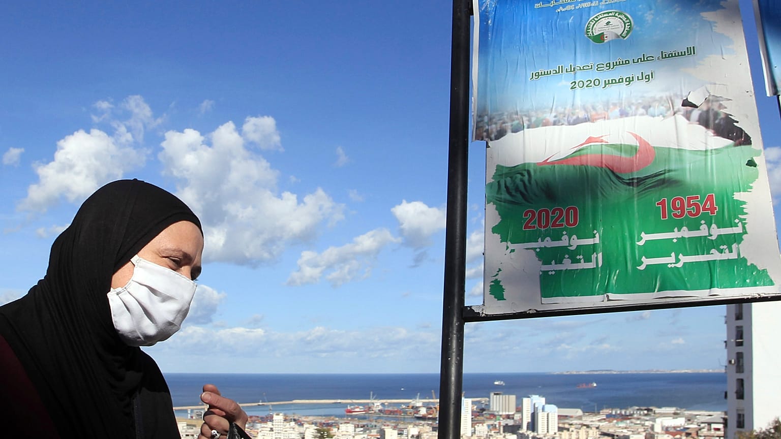A woman walks past posters promoting the vote for the upcoming referendum, Tuesday, Oct.27, 2020 in Algiers
