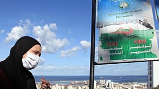 A woman walks past posters promoting the vote for the upcoming referendum, Tuesday, Oct.27, 2020 in Algiers