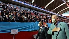 Turkey's President Recep Tayyip Erdogan, right, wearing a mask to help protect against the spread of coronavirus, greets his ruling party members gathered in a stadium, in Kay