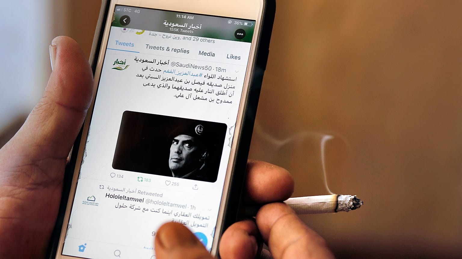 A man reads Saudi news on Twitter fronted by a picture of the prominent bodyguard to Saudi Arabia's King Salman Maj. Gen. Abdulaziz al-Fagham, at a coffee shop, in Jiddah