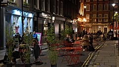 People dine outside on a street in central London, Saturday, Oct. 31, 2020. 
