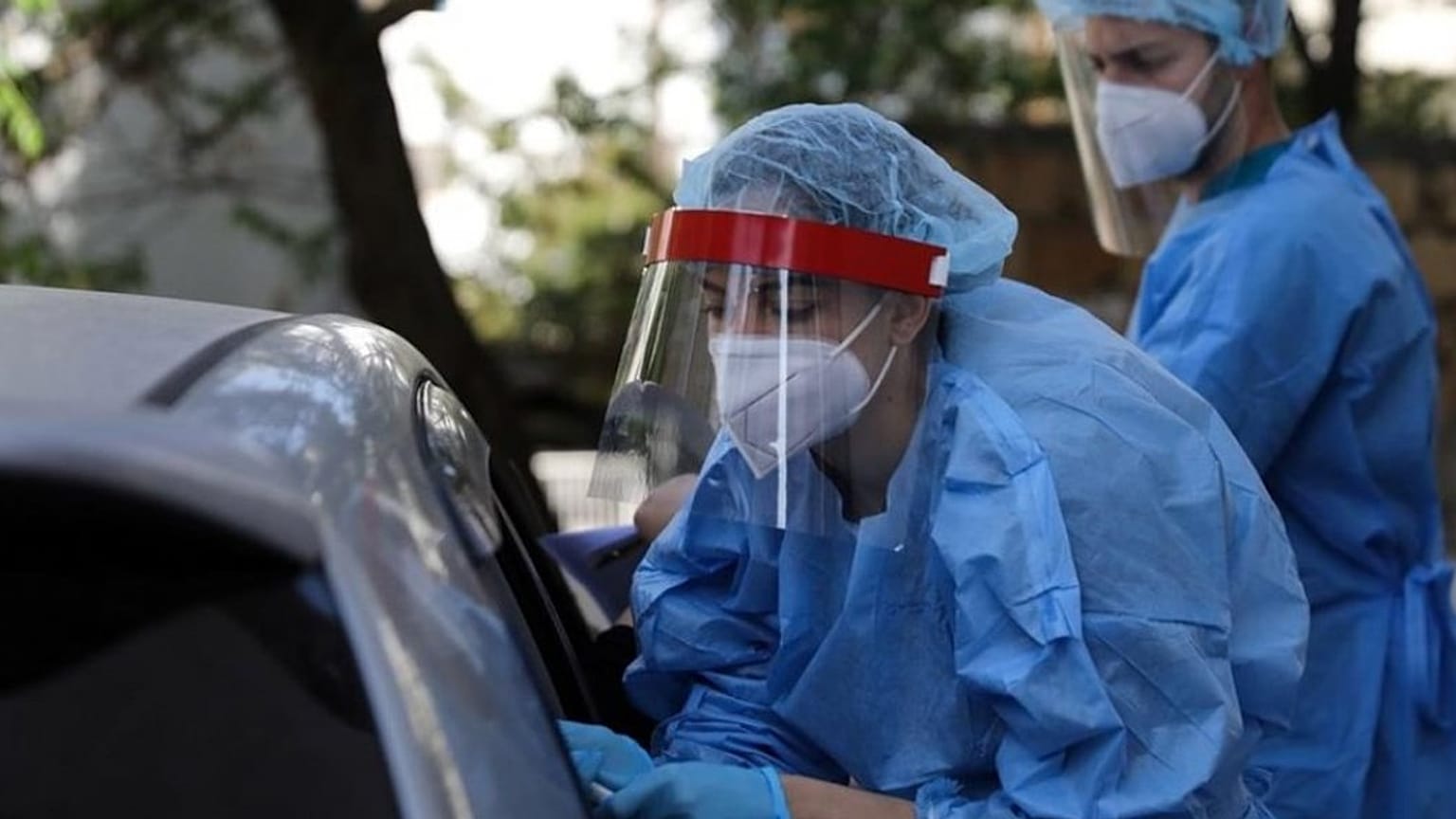 A medical worker wearing protective gear collects a swab from a commuter during rapid tests for COVID-19 at Syntagma station