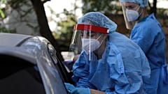 A medical worker wearing protective gear collects a swab from a commuter during rapid tests for COVID-19 at Syntagma station