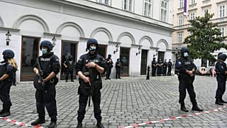 Police stand guard near a crime scene where wreaths have been displayed to pay respects to the victims in the center of Vienna on November 3, 2020, 