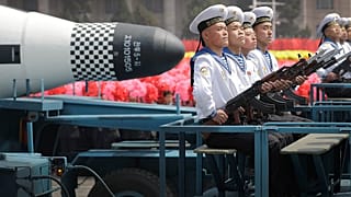 Kuzey Kore Donanma'ına bağlı personel, askeri geçit töreninde denizaltından fırlatılan "Pukguksong" balistik füzesinin (SLBM) önünde otururken