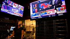 Bartender Sam Schilke watches election results on television at a bar and grill Tuesday, Nov. 3, 2020, in Portland, Ore. (AP Photo/Paula Bronstein)