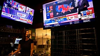Bartender Sam Schilke watches election results on television at a bar and grill Tuesday, Nov. 3, 2020, in Portland, Ore. (AP Photo/Paula Bronstein)
