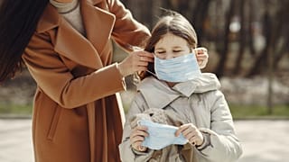 Çocuğuna maske takan bir anne
