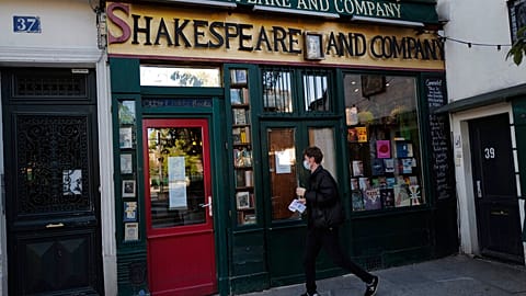 A man walks by the closed English and American literature Shakespeare and Co. bookstore in Paris, France, Thursday, Nov. 05, 2020.