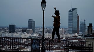 A woman balances on a railing on a hill above Lyon, France, which is in a monthlong partial lockdown