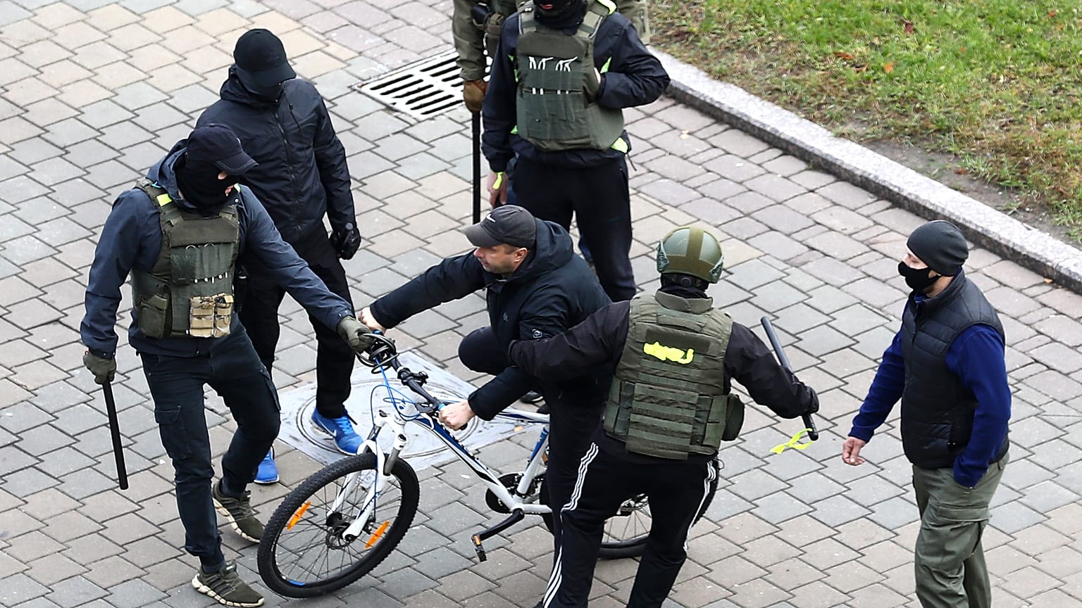 Ein Demonstrant in Minsk wird am Sonntag von maskierten Sicherheitskräften in die Zange genommen