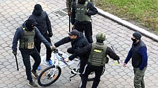 Ein Demonstrant in Minsk wird am Sonntag von maskierten Sicherheitskräften in die Zange genommen