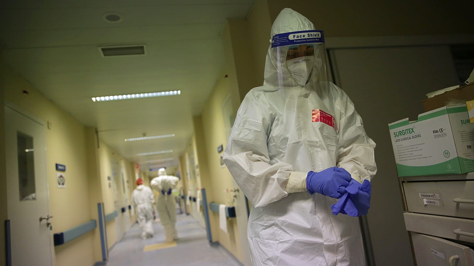 A nurse puts on a second pair of gloves before doing a round tending to COVID-19 patients in Lisbon.