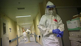 A nurse puts on a second pair of gloves before doing a round tending to COVID-19 patients in Lisbon.