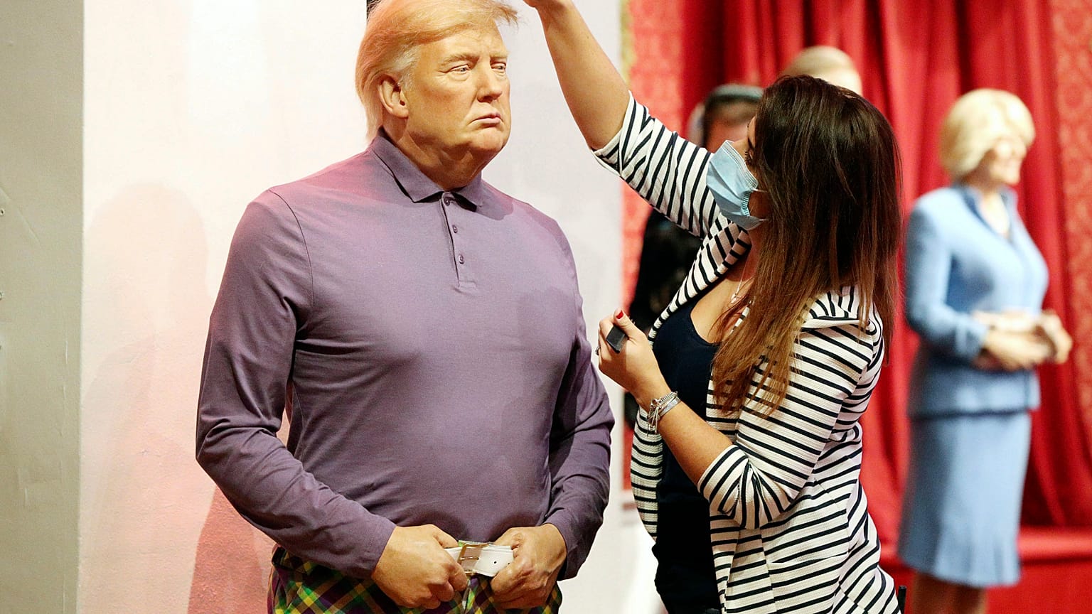 A member of the Madame Tussauds studios team places a set of golf clubs next to a wax figure of US President Donald Trump which has been re-dressed in golf wear.