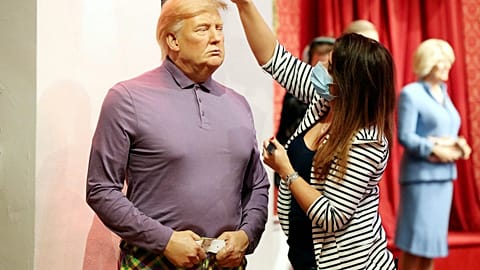 A member of the Madame Tussauds studios team places a set of golf clubs next to a wax figure of US President Donald Trump which has been re-dressed in golf wear.