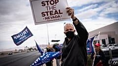 Supporters of President Donald Trump hold signs as they stand outside of the Clark County Elections Department in North Las Vegas, Nev. Saturday, Nov. 7, 2020.