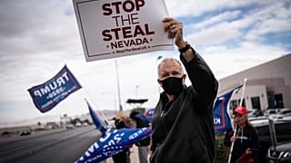 Supporters of President Donald Trump hold signs as they stand outside of the Clark County Elections Department in North Las Vegas, Nev. Saturday, Nov. 7, 2020.