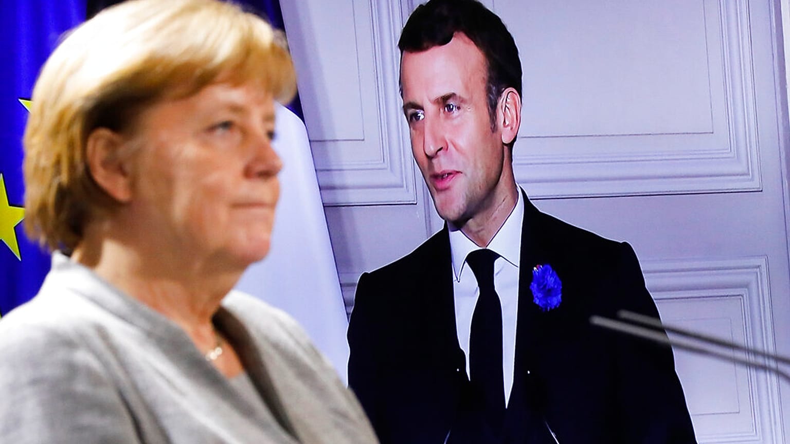 German Chancellor Angela Merkel listens to French president Emmanuel Macron, on the screen, during a virtual news conference with European leaders on terrorism