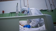 Ápoló védőfelszerelésben egy beteg pulzusát méri