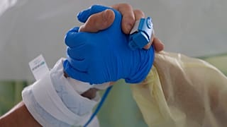 Therapeutin Catia Jesus hält die Hand einer Covid-Patientin auf der Intensivstation der Santa-Maria-Klinik in Lissabon