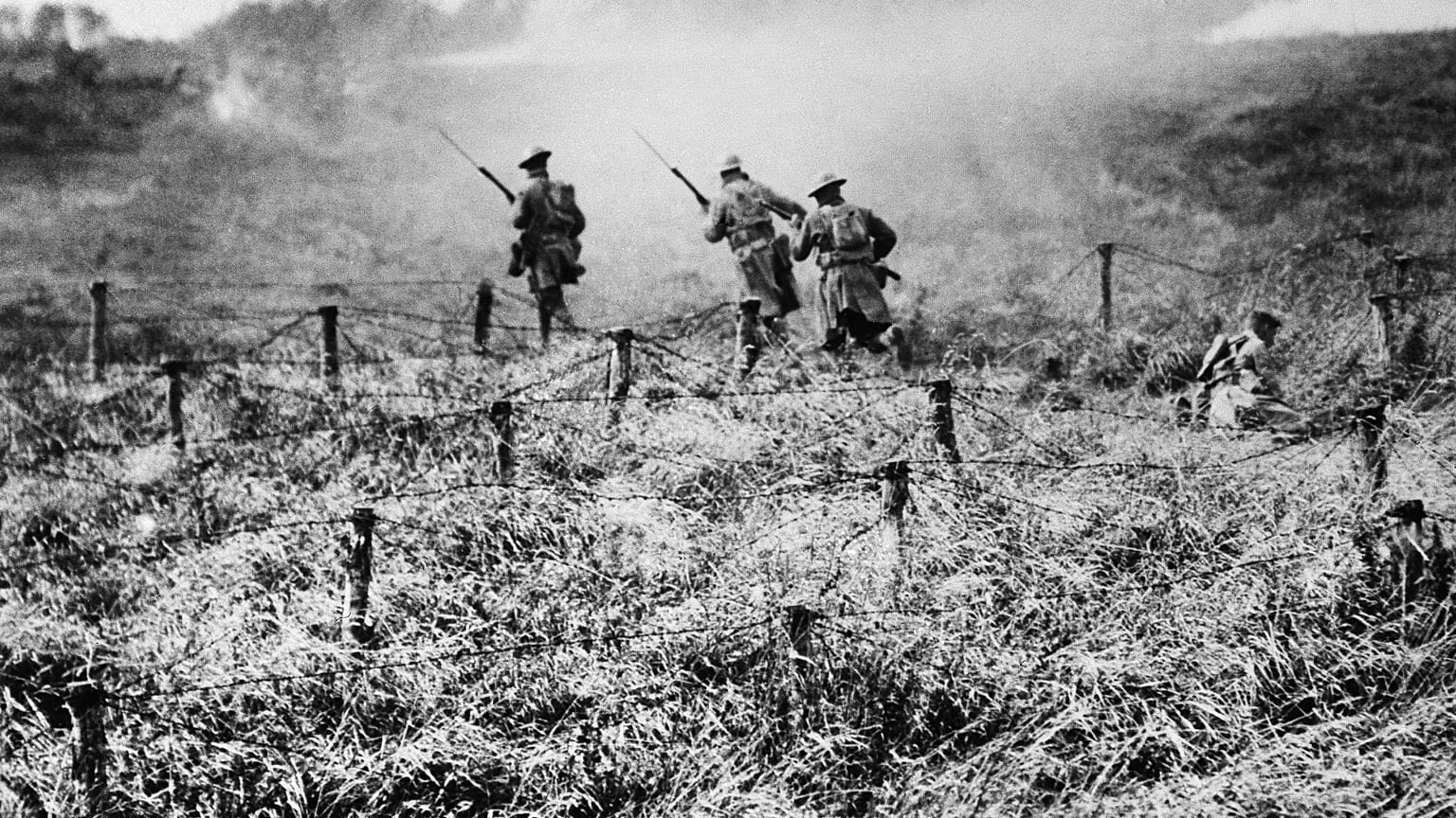 In this Sept. 13, 1918 file photo, U.S. troops of the 107th Regiment Infantry, 27th Division, advance on a path through a barbed wire entanglement near Beauqueanes, France.