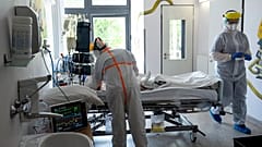 Védőfelszerelést viselő orvos és ápoló ellát egy beteget a koronavírussal fertőzött betegek fogadására kialakított osztályon