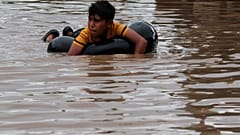 Un niño se tumba sobre un neumático hinchado en una calle inundada de Planeta, en Honduras