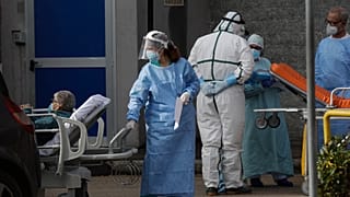 A paramedic carries a patient outside the first aid area of the Cardarelli hospital in Naples, Italy, Friday, Nov. 13, 2020