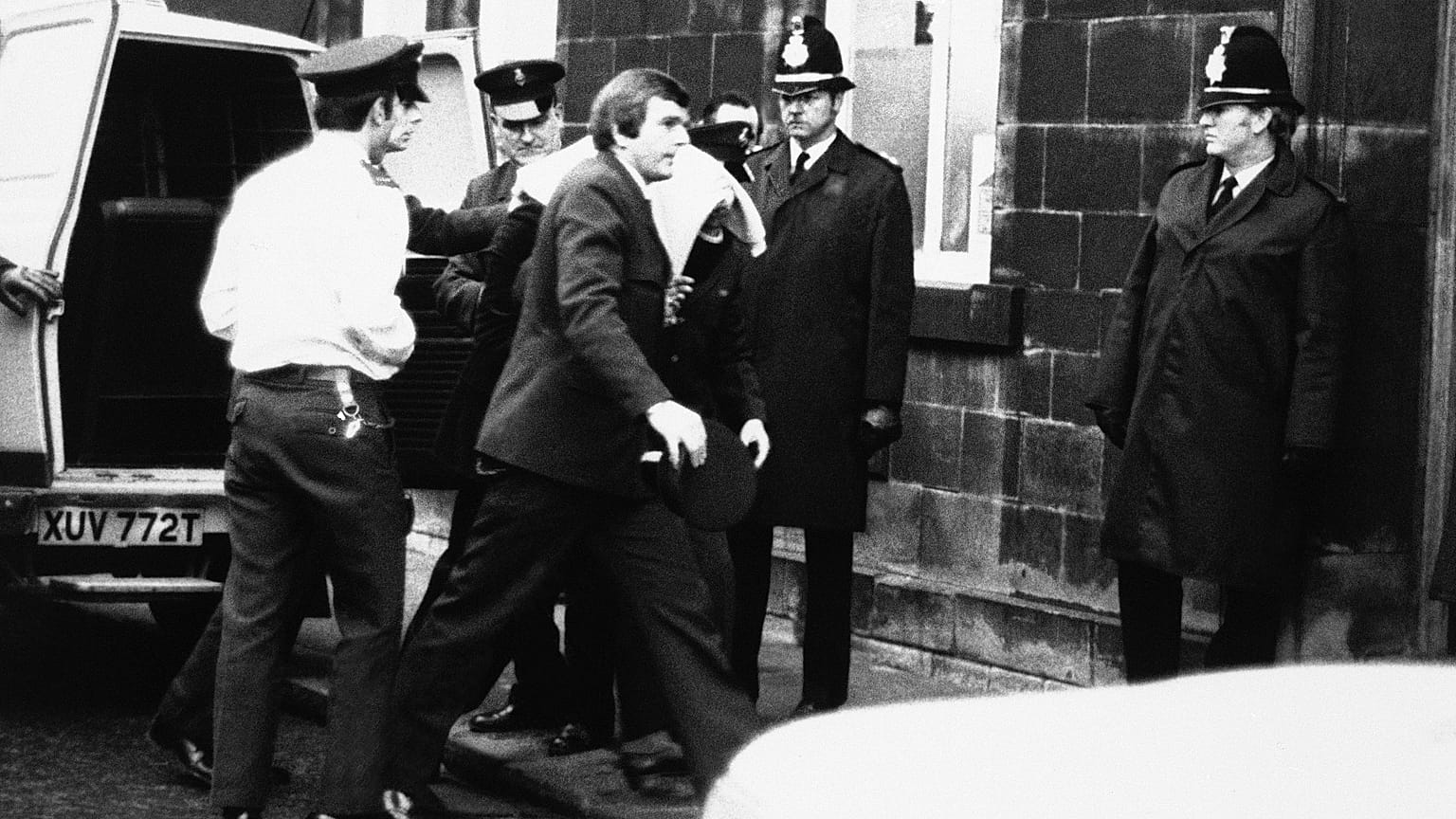 Peter William Sutcliffe (blanket on head) in Dewsbury in February 1981, where at the Magistrates Court he was committed in custody for trial on 13 counts of murder. 
