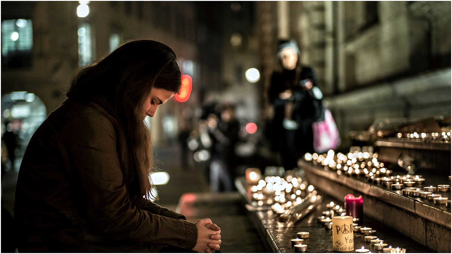 صورة لسيدة تصلي لأرواح ضحايا الهجوم عام 2015