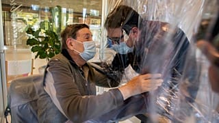 Relatives at a nursing home in Italy hug each other through a plastic film screen to avoid contracting COVID-19