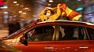 People drive cars and wave national flags celebrating the nation's qualification for EURO 2020, in a street in Skopje, North Macedonia, late Thursday, Nov. 12, 202O.