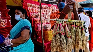 A man wearing a face mask sells sheaves of rice used to perform rituals during Diwali, the Hindu festival of lights, in Kolkata, India, Saturday, Nov. 14, 2020.  