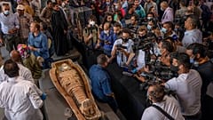 Journalists gather around an ancient sarcophagus more than 2500 years old, discovered in a vast necropolis.
