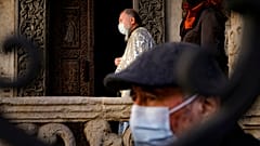 A priest wearing a mask for protection against the COVID-19 infection stands outside the Stavropoleos church, built in 1724, in Bucharest, Romania, Sunday, Nov. 8, 2020