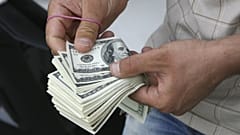 شمارش اسکناس‌های دلار توسز یک فروشنده ارز در بازار تهران