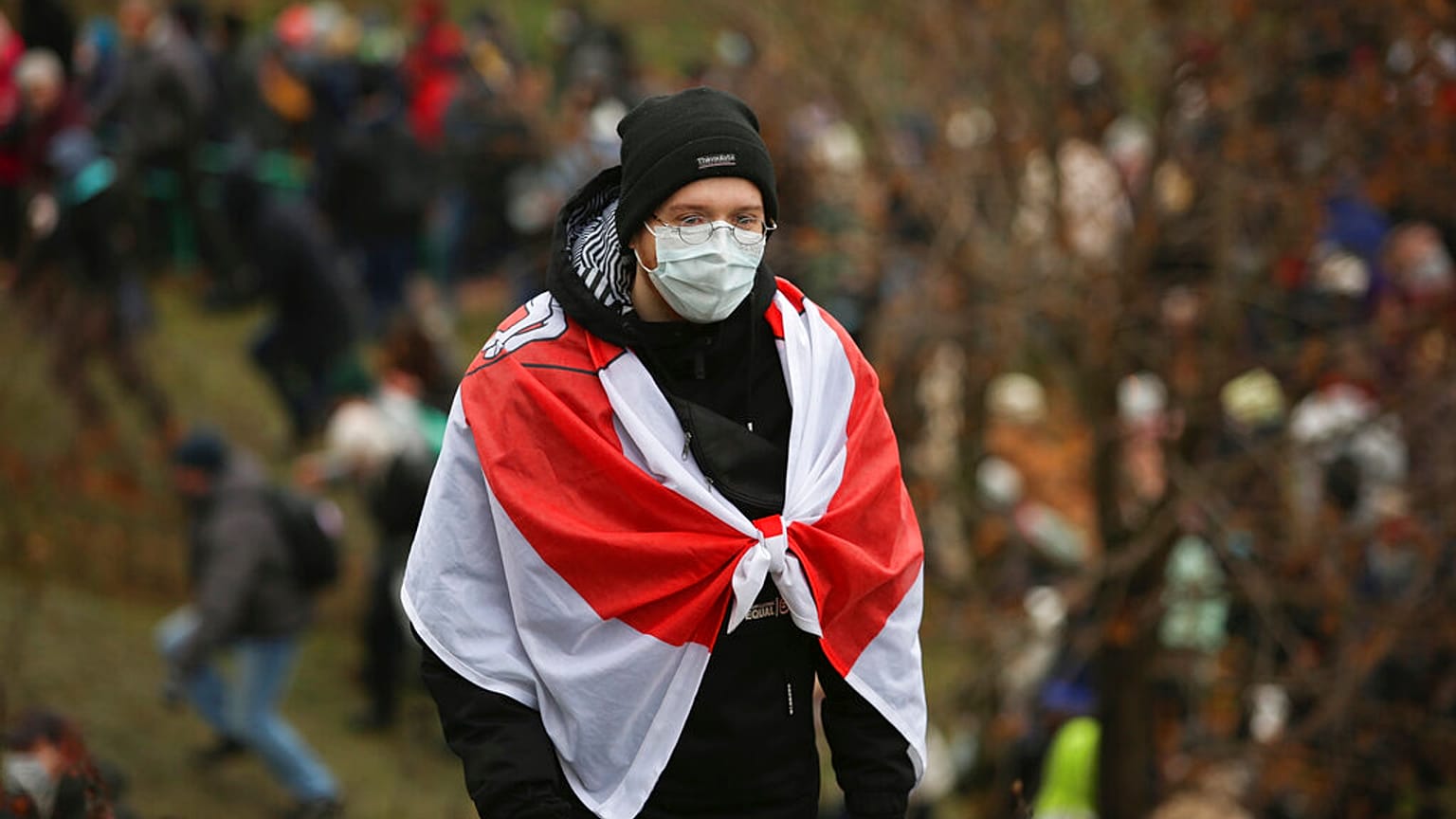 A demonstrator covering himself with an old Belarusian national flag stands during an opposition rally to protest the official presidential election results in Minsk, Belarus,