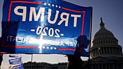 A supporter of President Donald Trump holds a Trump 2020 flag outside the U.S. Capitol building as they attend pro-Trump marches, Saturday Nov. 14, 2020, in Washington. (AP Ph