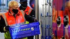 Britain's Prime Minister Boris Johnson loads a delivery van with a basket of shopping during a visit to a tesco.com distribution centre in London, Wednesday, Nov. 11, 2020. 