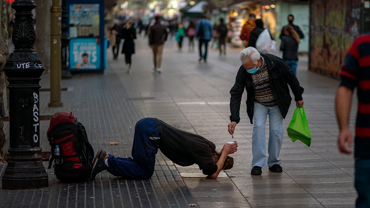 Un passant donne de l'argent à un mendiant sur les Remblas à Barcelone, le 12 novembre 2020